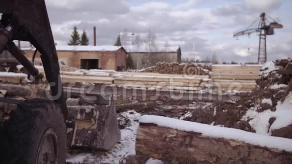 锯木厂的挖掘机储存堆被雪覆盖的木材材料视频的预览图