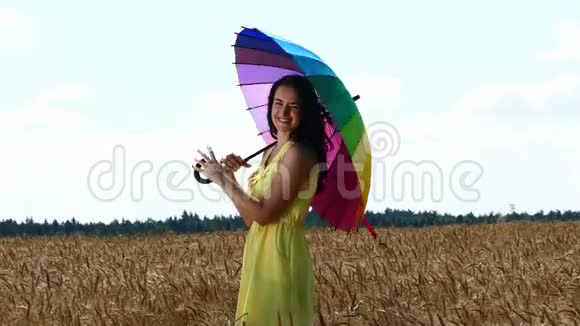 美丽的女孩在黄色的麦田上用紫色的伞奔跑视频的预览图