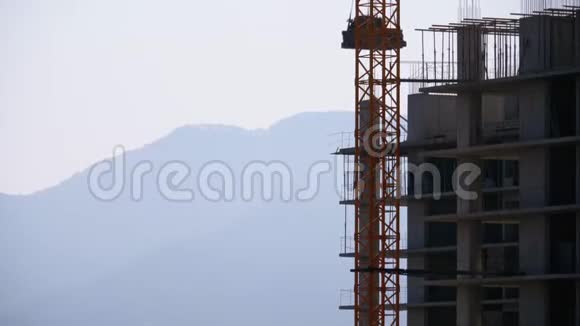 建筑工地上的塔吊在高层建筑上吊起一个荷载视频的预览图