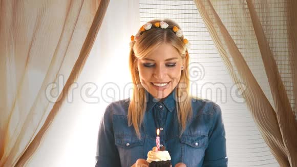 一个戴着派对帽的金发女郎在蛋糕上吹蜡烛视频的预览图