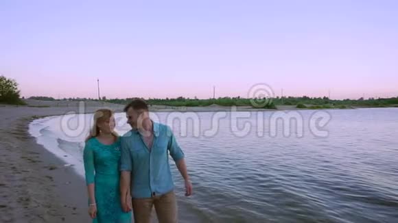 日落时分浪漫的情侣在海滩上散步视频的预览图