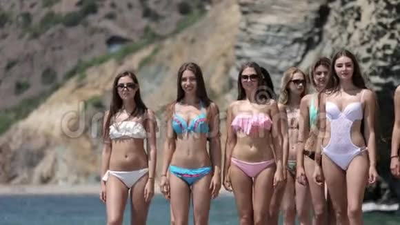 穿着比基尼的迷人年轻女性在海滩岸边奔跑视频的预览图