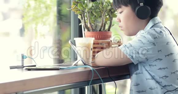 亚洲可爱的男孩用手机在杯子里喝牛奶微笑概念社交网络消息技术视频的预览图
