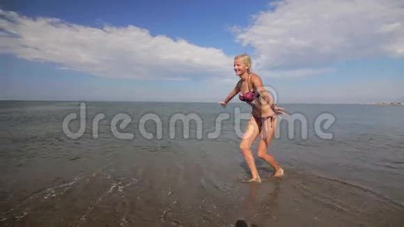 快乐的欧洲外观男孩穿着红色短裤在海滩上向他的母亲跑去他的母亲拥抱和转身视频的预览图