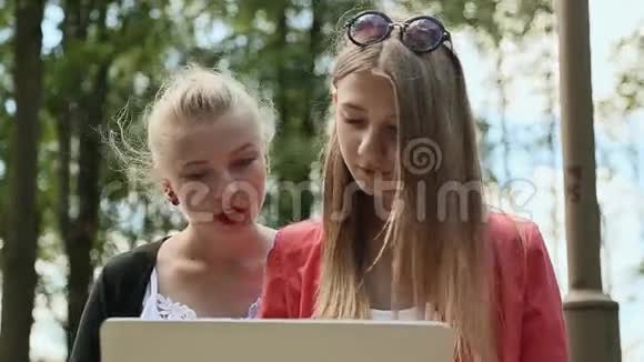 年轻漂亮女孩的脸大学女孩手里拿着笔记本电脑在绿色公园特写镜头视频的预览图