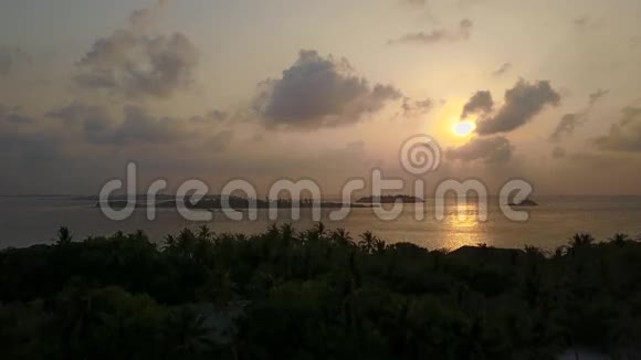 日落时的热带小岛空中景色照相机正在棕榈和海洋的轮廓上拍摄视频的预览图