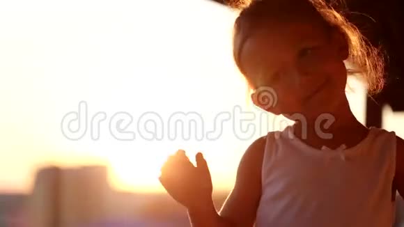 小女孩在阳台的夕阳下跳舞剪影特写镜头视频的预览图