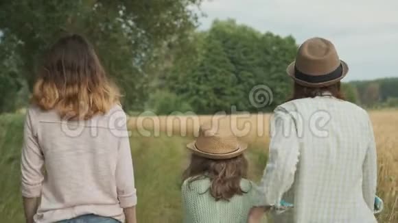 家庭母亲和孩子两个女儿一起走在乡间小路上后景视频的预览图