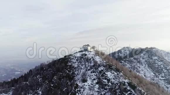 在秋天或冬天在日落时在雪山的顶部建造或教堂松树林和森林视频的预览图