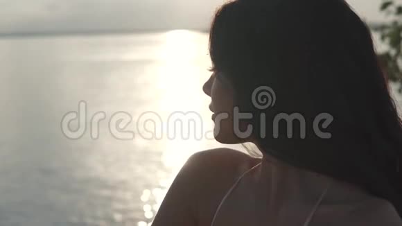 在夕阳的照耀下一个美丽的女孩的特写肖像以一个女孩为背景的剪影视频的预览图