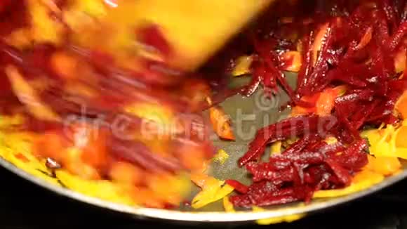 细碎的甜菜和胡萝卜用油煎锅煎用木抹子搅拌视频的预览图