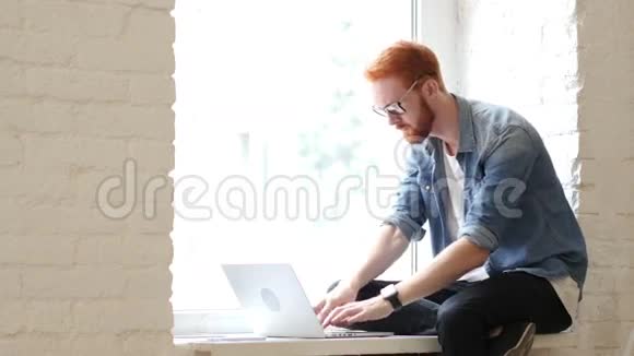 失败在笔记本电脑上工作沮丧的人坐在窗户上视频的预览图