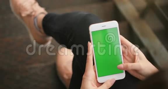 女孩使用手机绿色屏幕户外城市环境红色电影院4K手握商务智能手机视频的预览图