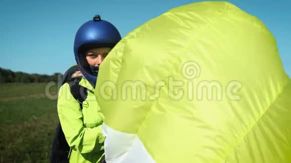 滑翔伞女孩滑翔伞准备在一座绿色的小山上起飞着陆后携带降落伞视频的预览图