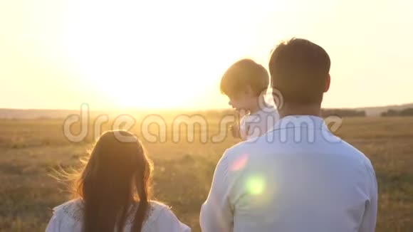 日落时分爸爸和妈妈和她的女儿抱在怀里散步一家人在日落时带着一个孩子散步有女儿的父亲视频的预览图