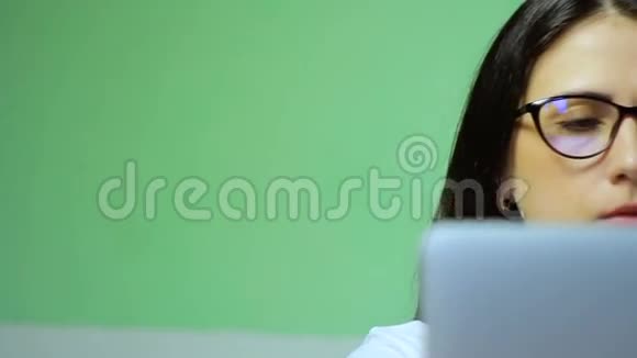 年轻的黑发女人戴着眼镜在笔记本电脑上工作高清镜头视频的预览图