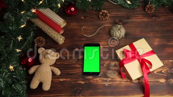 木制背景上景黑色智能手机绿色屏幕躺在桌子上上面假日装饰视频的预览图