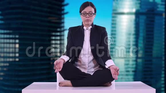 办公室里年轻商务女性的肖像她坐在桌上坐在莲花的位置上沉思着做生意视频的预览图