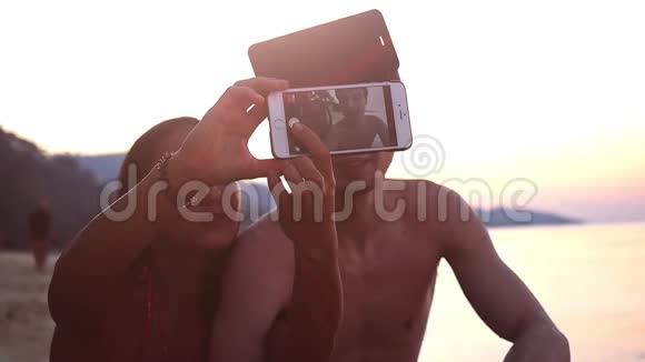 热带海滩美丽的日落期间几个最好的朋友用手机自拍慢动作高清高清视频的预览图