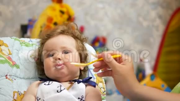 在她最喜欢的房子里快乐的孩子用勺子喂婴儿视频的预览图