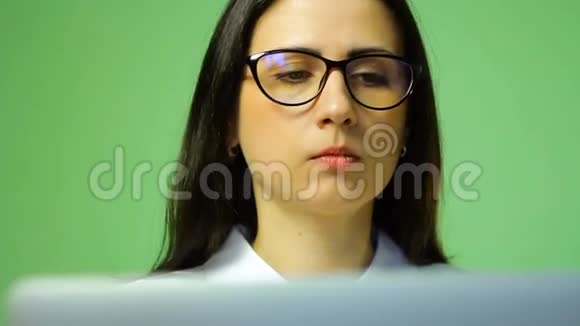 年轻的黑发女人戴着眼镜在笔记本电脑上工作高清镜头视频的预览图