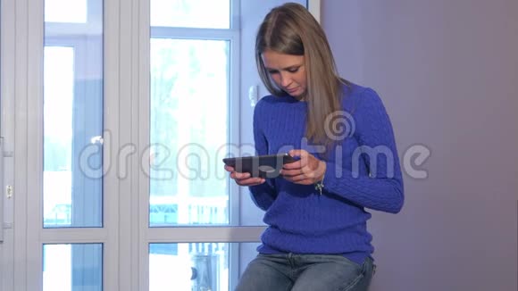一位严肃的女士坐在酒店大堂的手提箱里一边使用数码平板电脑视频的预览图