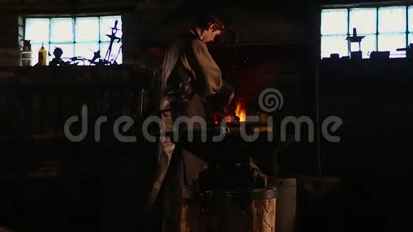 铁匠从炉子里取出一滴铁水当他敲打一块白色的铁水时会产生一阵火花视频的预览图