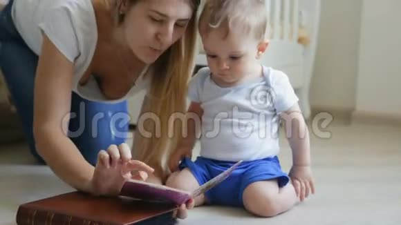 漂亮的年轻妈妈在客厅的地板上给她的小儿子读一本书视频的预览图