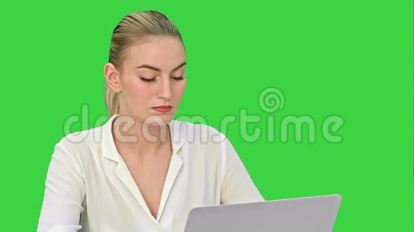 年轻的金发女商人在绿色屏幕上的笔记本电脑上工作Chroma键视频的预览图