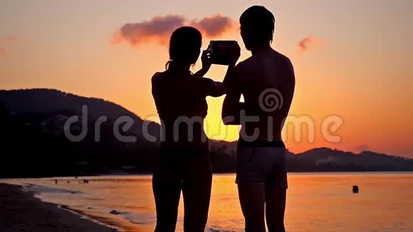 情侣自拍剪影在惊人的日落通过电话慢动作高清1920x1080视频的预览图