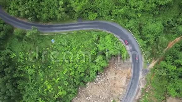 驾驶摩托车的司机在青山旁的弯道上驾驶汽车视频的预览图