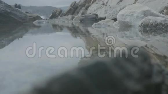 平静的水上倒影海岸岩石景观视频的预览图