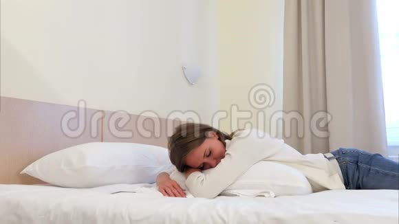 睡在酒店房间的白色床上的放松的漂亮年轻女人视频的预览图
