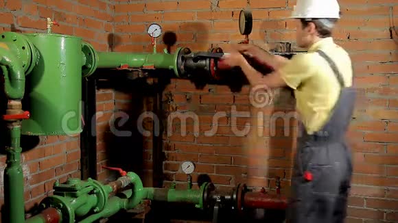 工作服的工人关闭水阀人关掉锅炉房的暖气视频的预览图