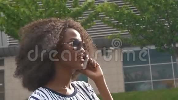 年轻迷人的非洲裔美国商界女性戴着太阳镜在手机上交谈微笑着视频的预览图