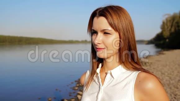 画像女子站在江岸河岸上微笑的女人的肖像近点视频的预览图