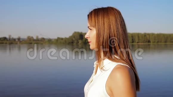 画像女子站在江岸河岸上微笑的女人的肖像近点视频的预览图