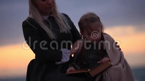 海边带着女孩看书的女人视频的预览图