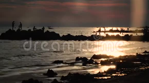 夕阳下的人们沐浴在海边的小船上海浪拍打着海岸视频的预览图
