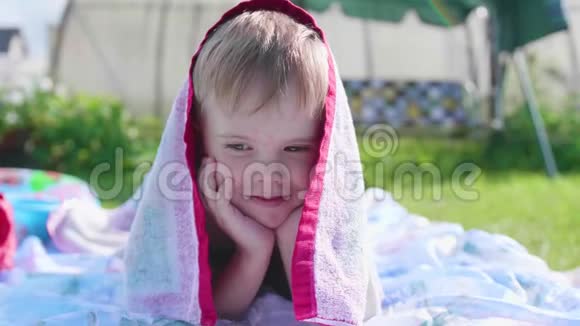 一个小男孩在炎热的夏天躺在草坪上玩耍4这个孩子玩得很开心也很活跃视频的预览图