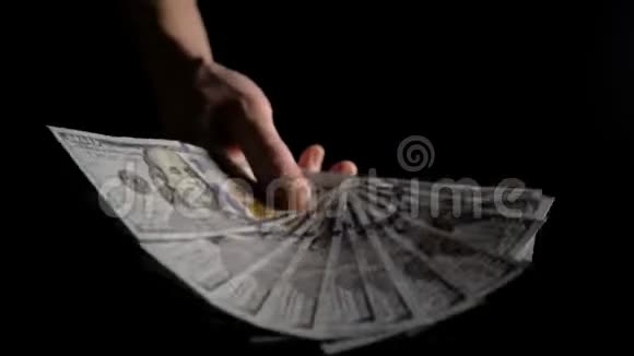 一个人在黑暗中挥舞着一把美元的扇子4K慢动作视频的预览图