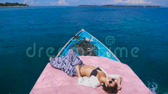 在开阔的海面上小游艇的甲板上靠近迷人的模型日光浴穿着黑色泳衣的年轻女孩视频的预览图
