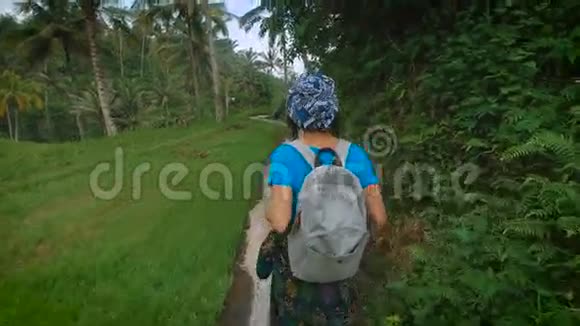 年轻女子背着背包在丛林的绿色中沿着石径散步游客正在积极寻找视频的预览图