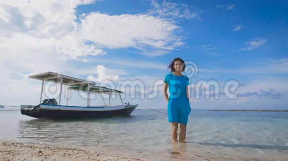 海洋上穿蓝色裙子的女孩在绿松石的背景下干净的海洋游艇和晴朗的天空巴厘岛视频的预览图