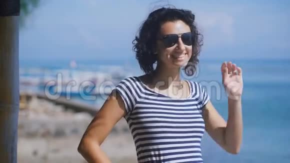 在夏天阳光明媚的日子里一个美丽的黑发和蓝色海洋的短卷曲头发的特写青年视频的预览图