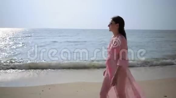 美丽的女性穿着一件长着粉红色连衣裙在岩石上的海滩上走来走去特写镜头4k视频的预览图