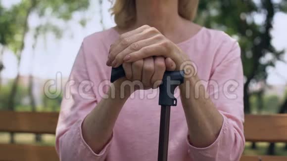 伤心的奶奶倚着手杖坐在公园的长凳上养老院视频的预览图
