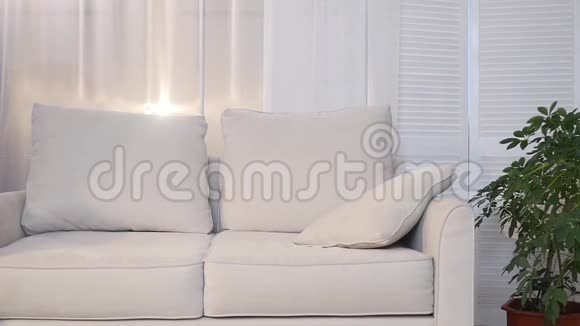 美丽的年轻女子躺在沙发上躺在家里的毯子下对着镜头微笑视频的预览图