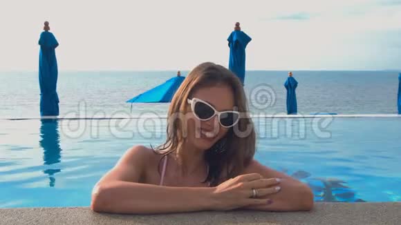 年轻白种人女子在游泳池微笑的肖像完美假期概念视频的预览图
