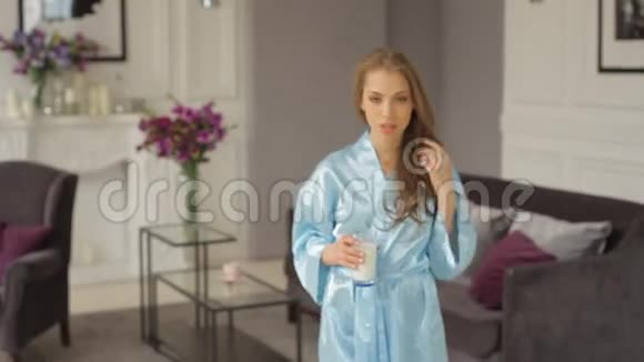 身穿蓝色长袍的魅力女郎走近前来喝牛奶视频的预览图